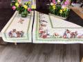 Nappe de Pâques fleurie, famille lapins et oeufs, frise vert anis, centrée sur fond beige, carrée 100x100 cm, polycoton jacquard
