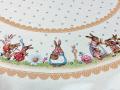 Nappe de Pâques fleurie, famille lapins et oeufs, frise bordeaux ou orange, centrée sur fond beige, ronde  Ø165 cm, polycoton jacquard